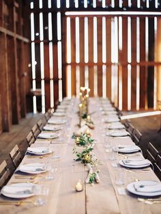 a long table with white plates and place settings