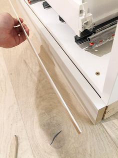 a person using a sewing machine to sew something on a table with wood flooring