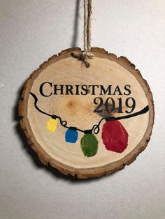 a christmas ornament hanging from a string on a tree slice with lights around it