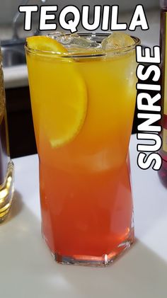 a tall glass filled with orange juice next to a bottle of teaquila sunrise