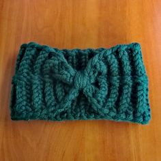 a crocheted headband with a knot on it sitting on a wooden table