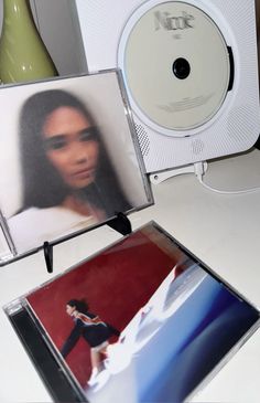 an album with a woman's face on the cover next to a cd player