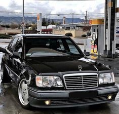 a black mercedes parked in front of a gas station with no one around the car