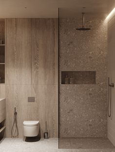 a bathroom with a walk in shower next to a white toilet and wooden wall behind it