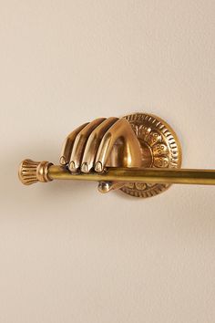 a gold toilet brush mounted to the side of a white wall