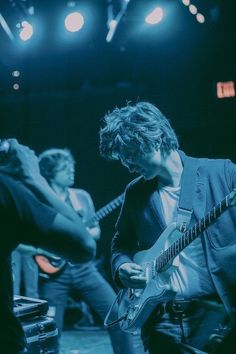 two men are playing guitars on stage