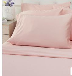 a bed with pink sheets and pillows on it