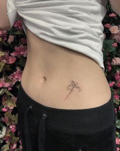 a woman's stomach with a small flower tattoo on her lower back and side