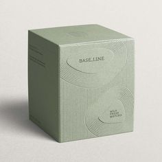 A cardboard soft green tea box with an embossed line pattern inspired by Kyoto gardens. It features the company, Baseline, logo and product description inside a pebble shape. Matcha Packaging, Visuell Identitet, Skincare Branding, Skincare Packaging, Perfume Packaging, Cosmetic Design