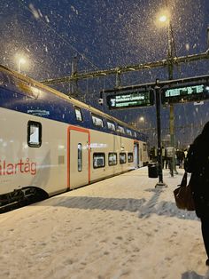 a person walking in the snow next to a train