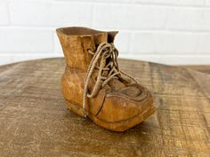 This charming carved wooden shoe, or boot, features intricate detailing and is accented with brown laces. It has eight holes for the laces, adding to its realistic appearance, and the open top creates a distinctive opening. The base is marked "DOC 83," indicating its origin from the 1980s. This unique piece makes a great decorative accent or a whimsical addition to any collection! 3 3/4 inches wide, 3 1/8 inches tall, and 1 3/4 inches deep. The small opening at the top is 1 1/4 inches tall by 3/4 of an inch in diameter. For size reference, the photos include a pack of 3 x 5-inch index cards. This weighs 3 ounces.  This vintage item may show signs of wear such as scuffs, marks, stains, and scratches. These imperfections are part of its charm and character. Also, it looks like it was handmad Wooden Shoe, Wooden Shoes, Index Cards, The 1980s, Open Top, Collectible Figurines, Unique Pieces, Accent Decor, Vintage Items