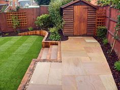 a garden with grass and wooden fenced in area next to the yard is shown