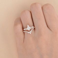 a woman's hand with a diamond ring on top of her finger and an engagement band