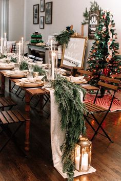 a dining room table decorated for christmas with candles and greenery on the table runner