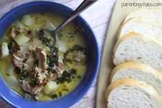 a blue bowl filled with soup next to sliced bread