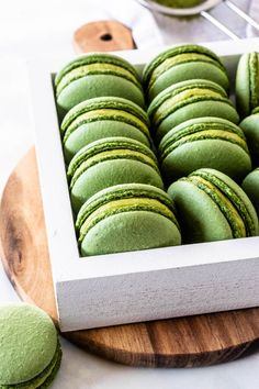 green macarons are in a white box on a wooden board with the words vegan matcha macaroons