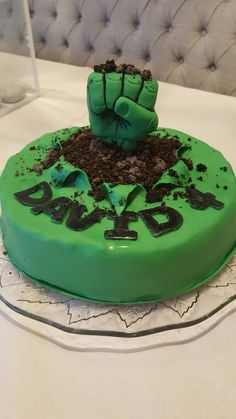 a cake with green frosting and dirt in the shape of a fist on top