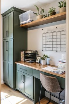 a kitchen with green cabinets and wooden counter tops, along with a desk that has a computer on it