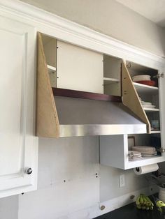 a kitchen with white cabinets and an open shelf above the stove top that has some bananas on it