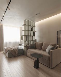 a living room filled with furniture and a book shelf next to a bed on top of a hard wood floor