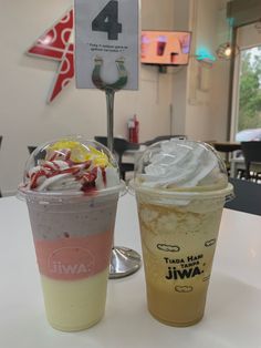 two drinks sitting next to each other on top of a white table in a restaurant