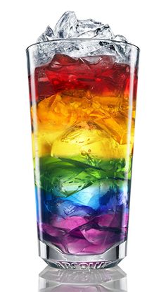 a rainbow colored drink in a tall glass filled with ice and water on a white background