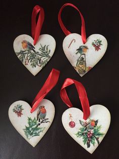 four heart shaped ornaments with red ribbon hanging from the sides on a black table top