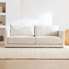 a white couch sitting on top of a hard wood floor next to a book shelf