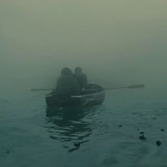 two people in a rowboat on a foggy day with the oars visible