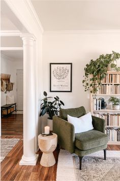 Living room decor consists of a green chair in the corner next to a full wooden bookshelf. There are lots of plants and a framed photo of a tree drawing on the wall. Style Deco, Decor Minimalist, Design Living Room, Living Room Inspo, A Living Room, Living Room Inspiration, Apartment Living, 인테리어 디자인, Home Decor Ideas