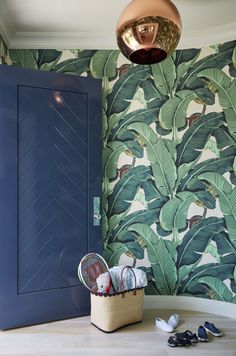 a blue door in front of a wallpapered room with green leaves on it