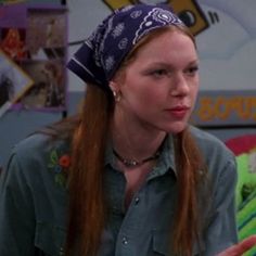 a woman with long red hair wearing a bandana on top of her head and looking off to the side