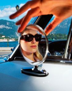 a woman's reflection in the side mirror of a car