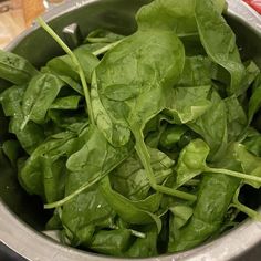 spinach leaves are in a silver bowl on the counter