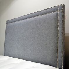 an upholstered headboard on a bed in a room with white walls and carpet