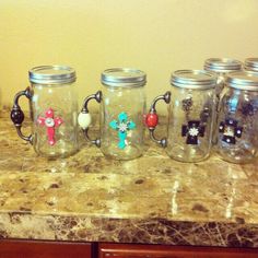 six glass mugs sitting on top of a counter with bead decorations in them