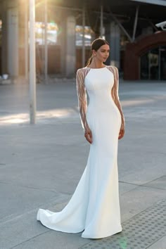 a woman in a white dress standing on the sidewalk