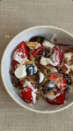 a bowl filled with fruit and yogurt on top of a beige table cloth