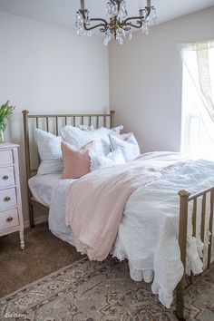 a bedroom with a bed, dresser and chandelier hanging from the ceiling in front of a window