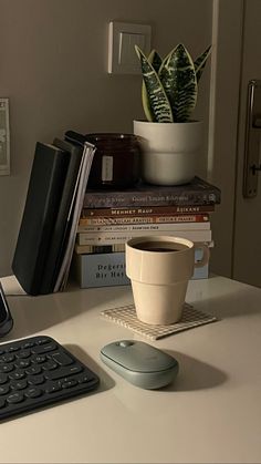 a computer keyboard sitting on top of a desk next to a cup of coffee and a cell phone