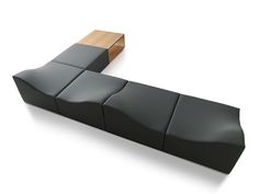 a black leather couch sitting next to a wooden table on top of a white floor