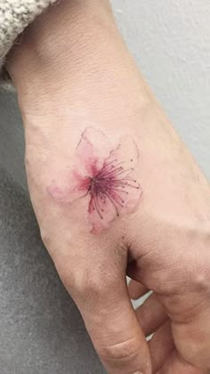 a person's hand with a flower tattoo on the left side of their palm