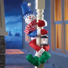 a snowman is hanging on the side of a light pole with stockings and mittens