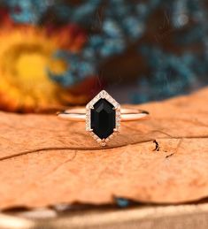 a black diamond ring sitting on top of a piece of wood with flowers in the background