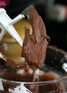 a spoon with chocolate frosting on it in a bowl