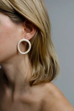 a woman with blonde hair wearing large white hoop earrings on her ear and looking off to the side