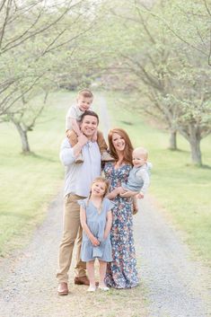 a family standing on a dirt road with trees in the background