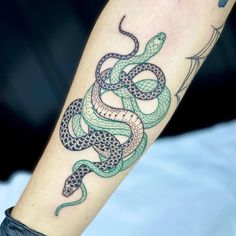 a green and black snake tattoo on the arm