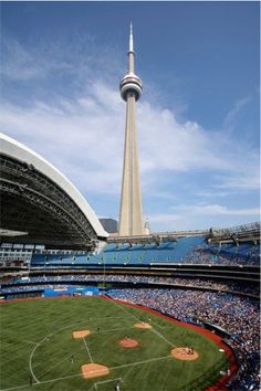 a baseball stadium filled with fans and a tall tower in the background that is also a sports field