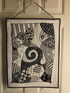 a black and white quilt hanging from a hook on a door handle with an abstract design